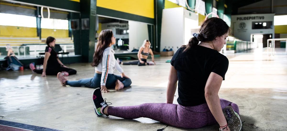 Women engaging in a group stretching session in an indoor gym.