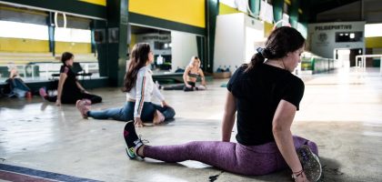 Women engaging in a group stretching session in an indoor gym.