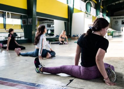 Women engaging in a group stretching session in an indoor gym.